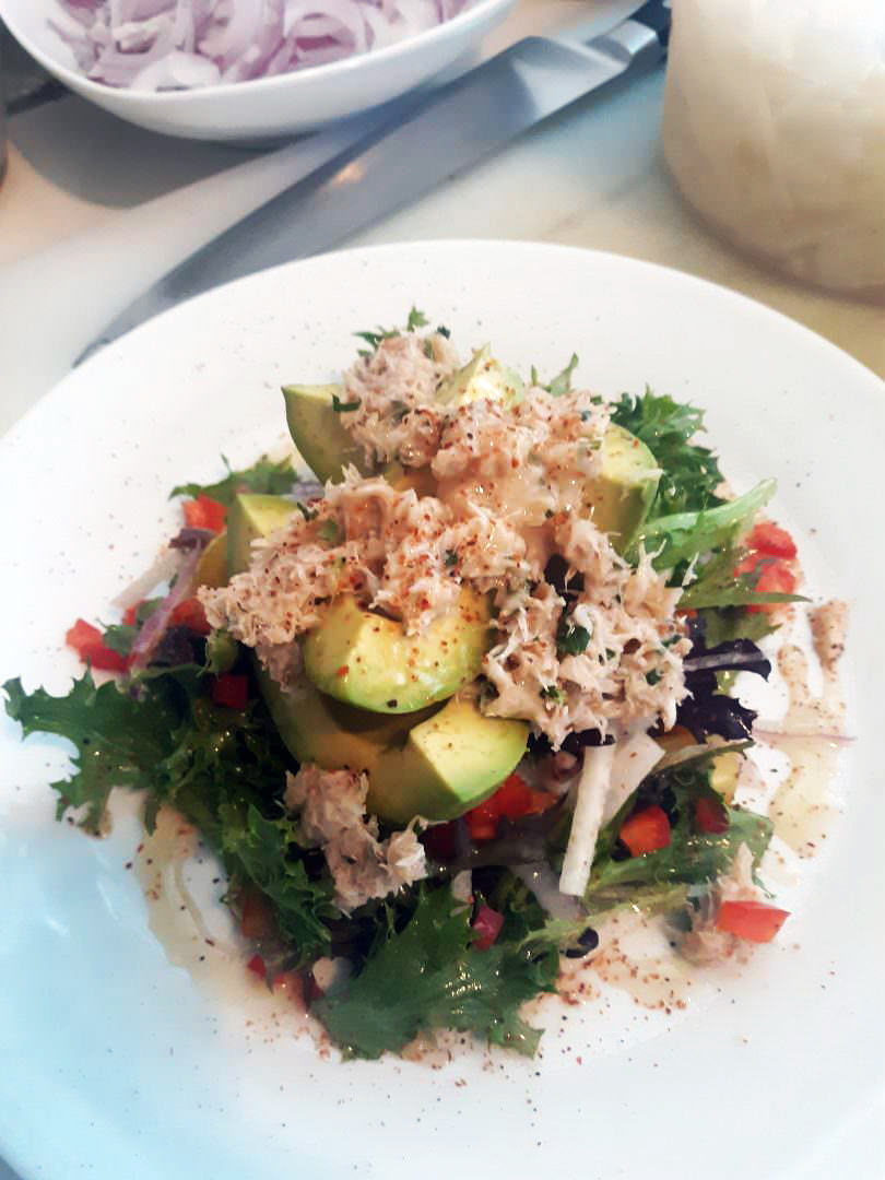 Avocado halves stuffed with herbed crab atop mixed greens, lightly dressed.