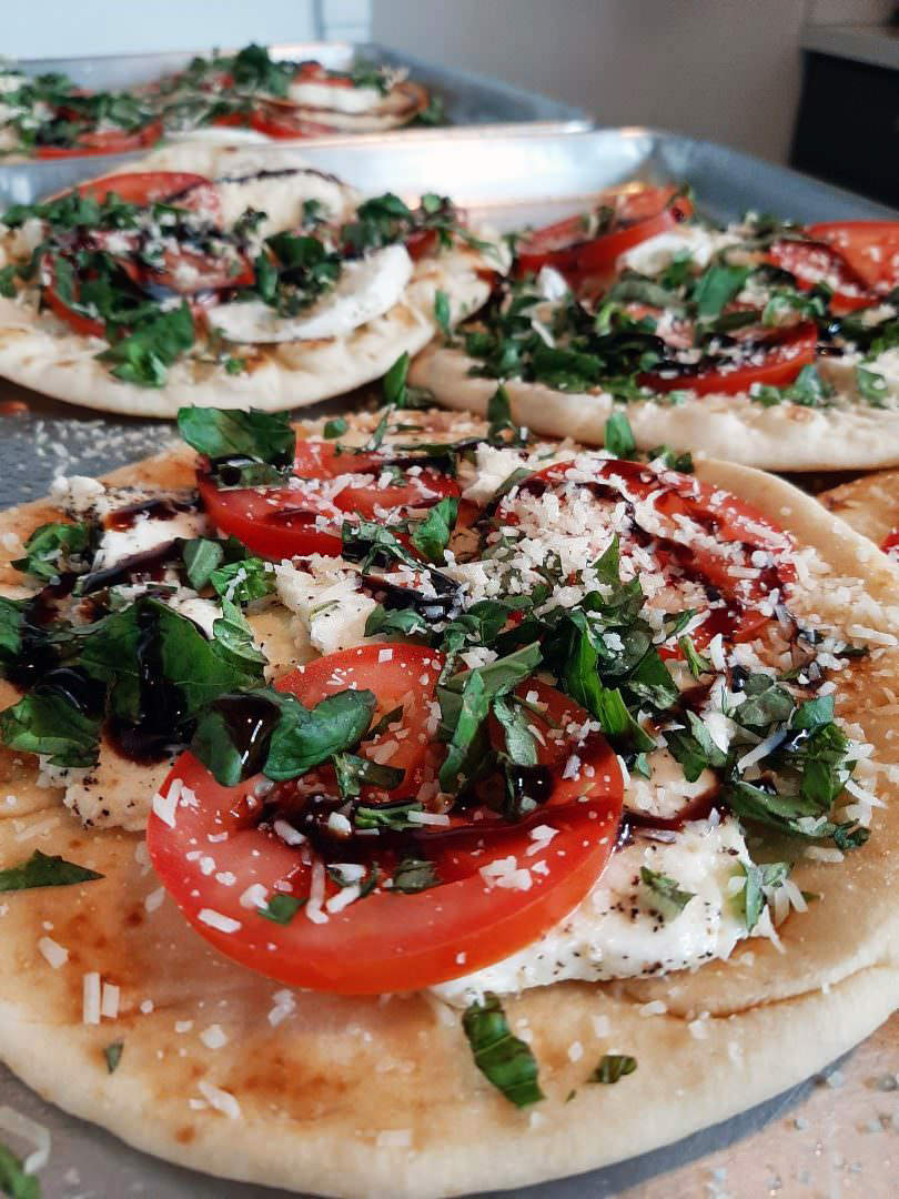 Caprese pita flatbread with mozzarella, tomato, basil, parmesan, and balsamic reduction.