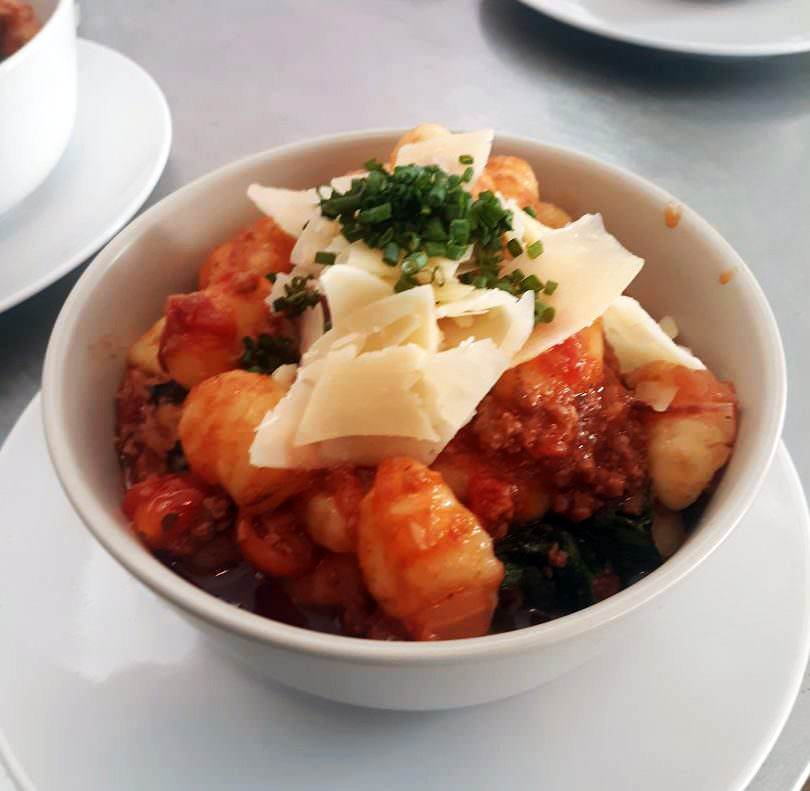 Pillowy gnocchi bolognese with wilted spinach, shaved parmesan, and chives.