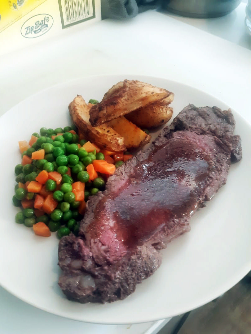 Medium-rare prime rib with red-wine jus, spiced potato wedges, and peas-carrots medley.