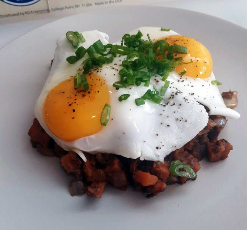 Sweet-potato hash crowned by two sunny-side eggs and sliced scallions.